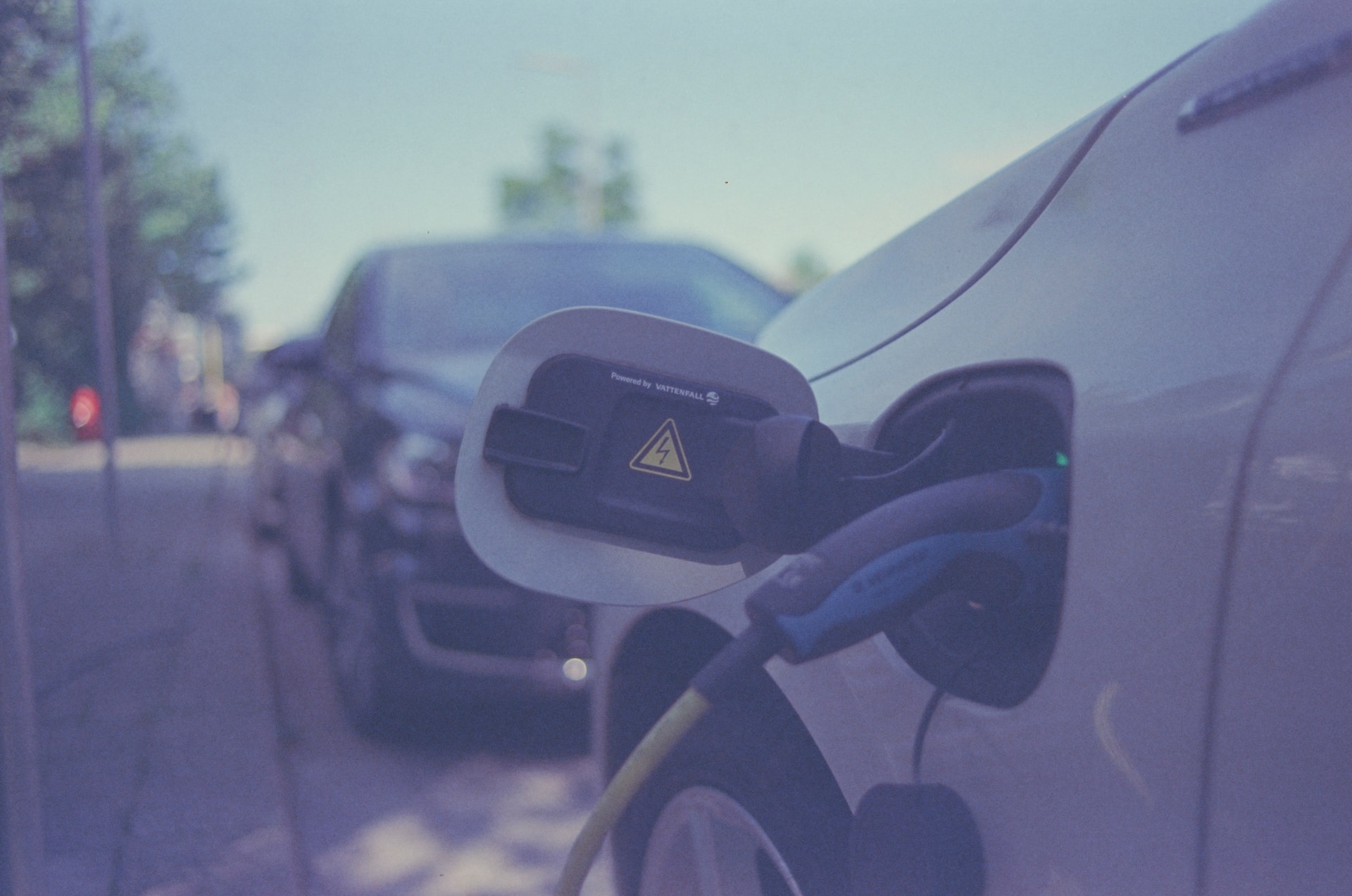 A close up of a car's electric charging port at a charging station
