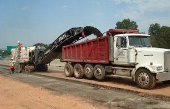 This photo shows a milling machine removing asphalt from existing I-85 to prepare for the grading necessary to build the new lanes of I-85. The asphalt is being recycled at an asphalt plant and reused in new asphalt mix.