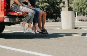 group of people sitting in the bed of a truck in a parking lot