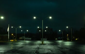 empty parking lot at night with lots of cracks and potholes.