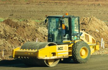 black and yellow road roller paving a new asphalt road.